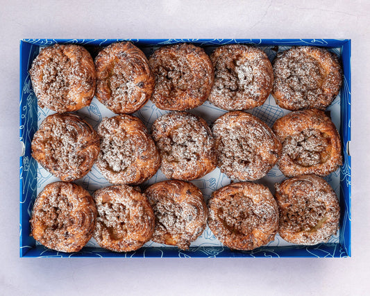 A box of mini apple crumble sourdough croissant danish with brown sugar topping.