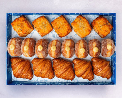 A catering pastry box with a selection of mini croissants, doughnuts, scones, Danishes, and cookies.
