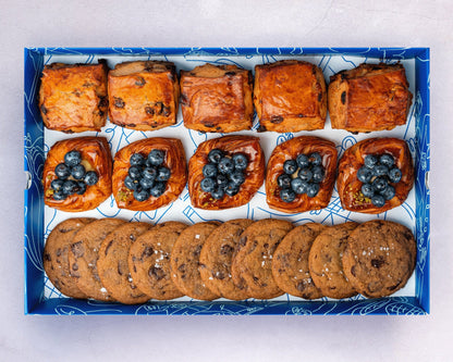 A box of Bakehouse Occasions afternoon tea treats with apple & raisin scones, mini blueberry danish, and chocolate sea salt cookies.
