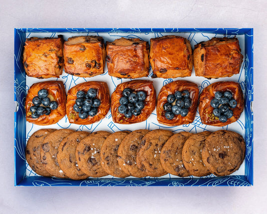 A box of Bakehouse Occasions afternoon tea treats with apple & raisin scones, mini blueberry danish, and chocolate sea salt cookies.