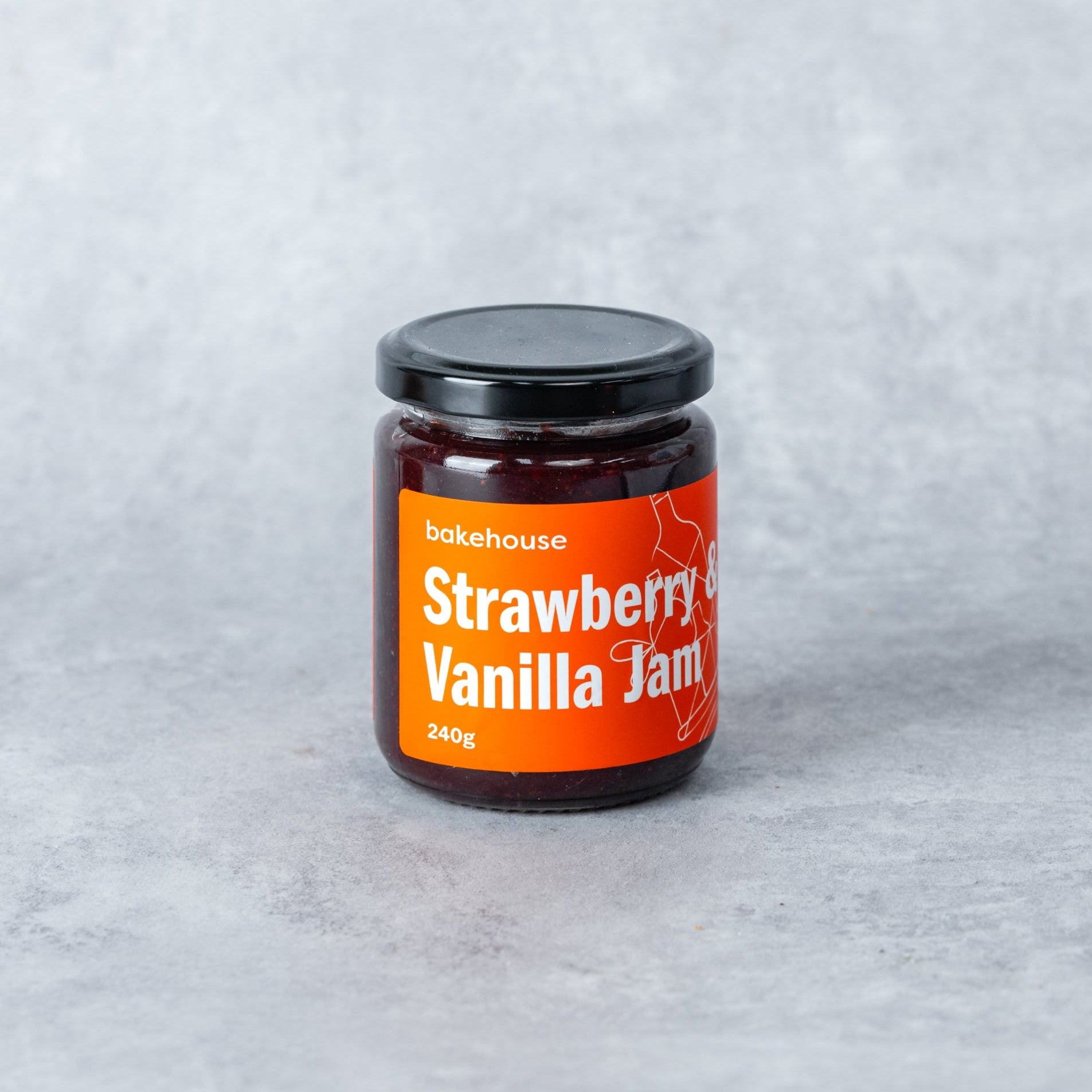 A jar of strawberry vanilla jam with a Bakehouse orange label.